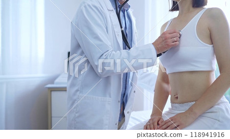 Doctor and patient. Physician is using stethoscope examining woman lungs in clinic cabinet. Medicine and health care Doctor and patient. Physician is using stethoscope examining woman lungs in clinic cabinet. Medicine and health care 118941916