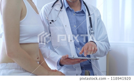 Doctor and patient. Physician is making notes on a clipboard while patient woman is describing something. Medicine concept 118941920