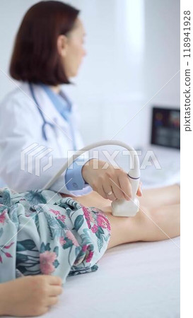 Doctor and kid patient. Orthopedist performing ultrasound examination on a child's knee in a clinic. Medicine and health care Doctor and kid patient. Orthopedist performing ultrasound examination on a child's knee in a clinic. Medicine and health care 118941928