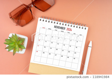 November 2024 desk calendar with brown sunglasses on beautiful background, Appointment concepts. November 2024 desk calendar with brown sunglasses on beautiful background, Appointment concepts. 118941984
