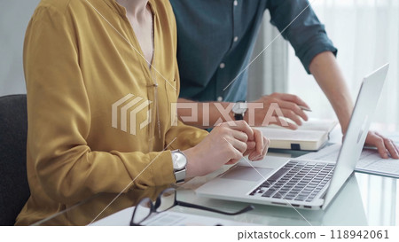 Team collaboration over financial reports. Business people, professionals analyzing financial charts and data on a desk while sitting near a laptop computer Team collaboration over financial reports. Business people, professionals analyzing financial charts and data on a desk while sitting near a laptop computer 118942061