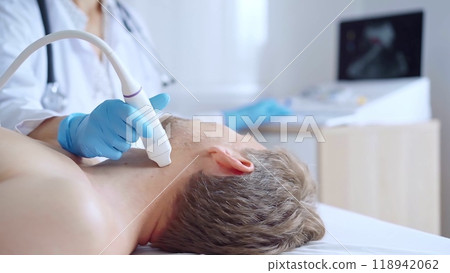 Doctor woman with a blue medic gloves performing neck ultrasound exam on male patient. Medicine service concept. Thyroid gland health Doctor woman with a blue medic gloves performing neck ultrasound exam on male patient. Medicine service concept. Thyroid gland health 118942062