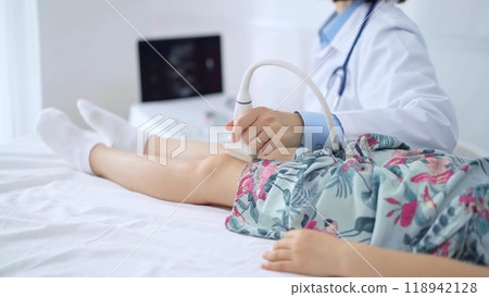 Doctor and kid patient. Orthopedist performing ultrasound examination on a child's knee in hospital. Medicine 118942128