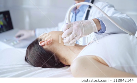 Doctor man is using ultrasound equipment on neck of female patient lying down for a medical examination. Medicine and science 118942144