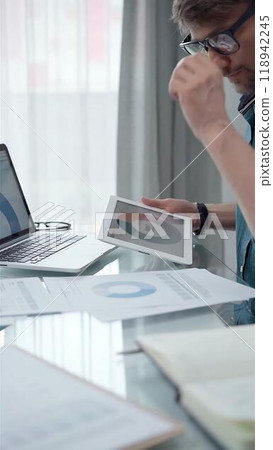 Businessman wearing green shirt and glasses is working with tablet computer and data analysis charts. Vertical business portrait 118942245