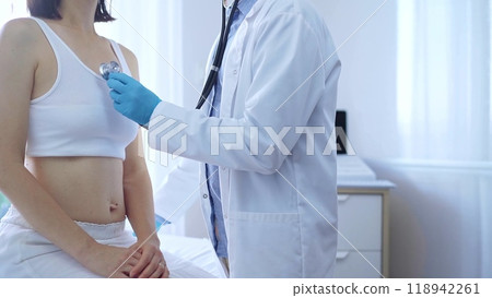 Doctor and patient. Physician wearing blue medical gloves is using stethoscope examining woman lungs in clinic. Medicine concept 118942261