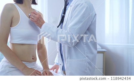 Doctor and patient. Physician is using stethoscope examining woman lungs in clinic cabinet. Medicine and health care 118942434