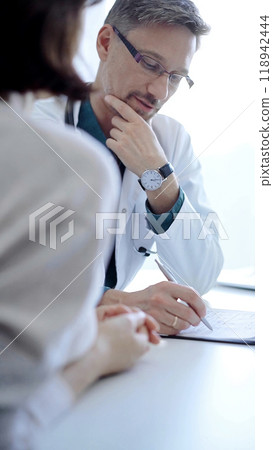 Doctor and a patient. The physician, wearing a white medical coat over a green shirt, gesturing with his hands during a consultation in the clinic. Medicine concept 118942444