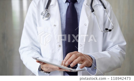 Doctor man wearing lab coat and stethoscope using tablet computer in hospital. Medicine and science 118942473