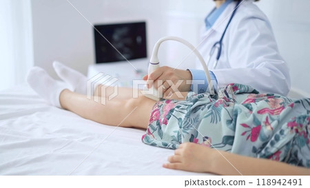 Doctor and kid patient. Orthopedist performing ultrasound examination on a child's knee in hospital. Medicine 118942491