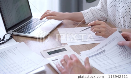 Business people professionals analyzing financial documents. Two colleagues working together, reviewing papers and using a laptop. Finance audit and taxes Business people professionals analyzing financial documents. Two colleagues working together, reviewing papers and using a laptop. Finance audit and taxes 118942511
