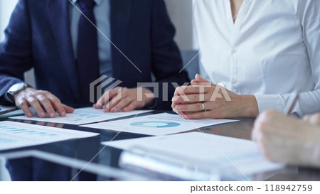 Business people wearing suits are reviewing a financial results and discussing the terms of the agreement. Teamwork and planning 118942759