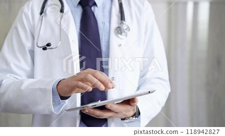 Doctor man wearing lab coat and stethoscope using tablet computer in hospital. Medicine and science 118942827
