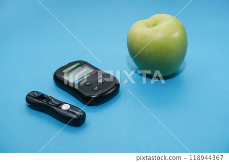 Diabetes concept. Glucose meter, apple on a blue background. World diabetes day concept. copy space 118944367