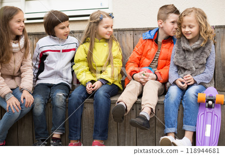Children on a bench playing Chinese whispers 118944681