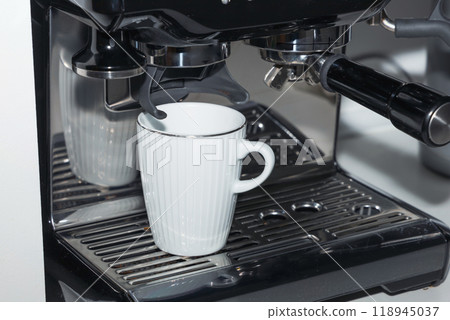 A white coffee cup pouring coffee into a coffee maker. 118945037