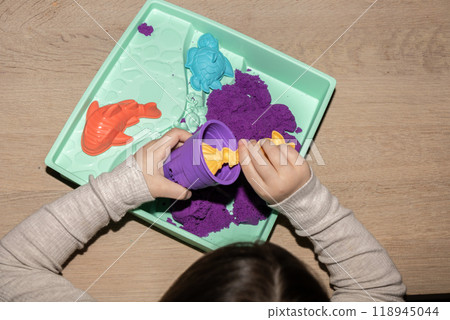 a child is playing with kinetic sand on a table 118945044