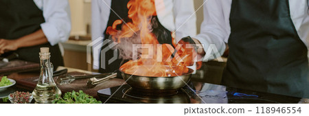 Header of unrecognizable sous chef cooking flambe steak in professional kitchen 118946554