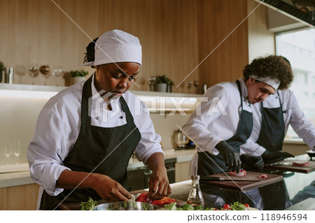African American female cook stuffing salmon with lemon while her colleagues cutting meat African American female cook stuffing salmon with lemon while her colleagues cutting meat 118946594