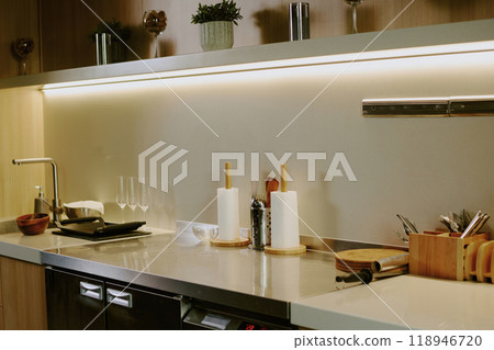 Wooden kitchen counter with kitchenware and dishes on white granite top 118946720