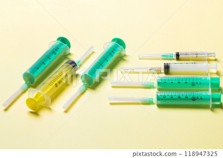 Top view of medical syringes with needles at yellow background with copy space. Injection treatment concept Top view of medical syringes with needles at yellow background with copy space. Injection treatment concept 118947325