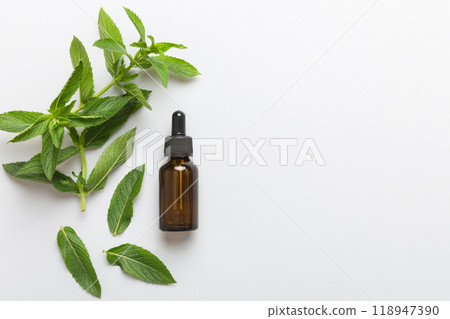 Natural Mint Essential Oil in a Glass Bottle. organic cosmetics with herbal extracts of mint on colored background 118947390