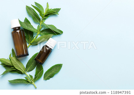 Natural Mint Essential Oil in a Glass Bottle. organic cosmetics with herbal extracts of mint on colored background 118947391