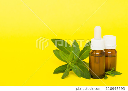 Natural Mint Essential Oil in a Glass Bottle. organic cosmetics with herbal extracts of mint on colored background 118947393