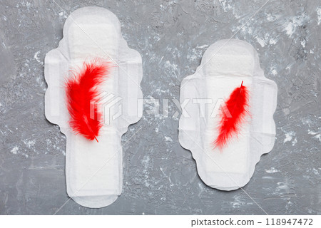 Women hygiene products or Sanitary pad with red feather on colored background. Pastel color. Closeup. Empty place for text. Female daily hygiene 118947472