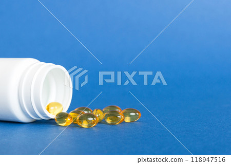 Soft gels pills with Omega-3 oil spilling out of pill bottle close-up. Gel capsules bottle white surface. Omega 3, multivitamins, Calcium, antibiotics. Health. Immunity Soft gels pills with Omega-3 oil spilling out of pill bottle close-up. Gel capsules bottle white surface. Omega 3, multivitamins, Calcium, antibiotics. Health. Immunity 118947516