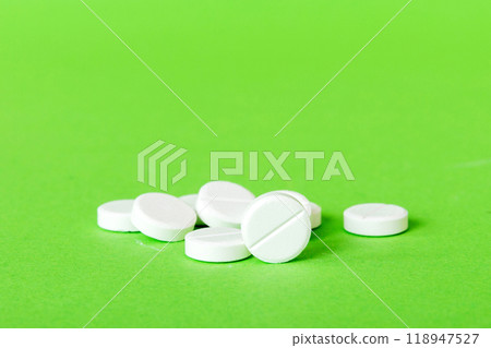 Heap of white pills on colored background. Tablets scattered on a table. Pile of red soft gelatin capsule. Vitamins and dietary supplements concept 118947527