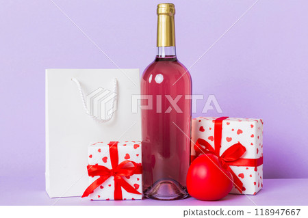 Bottle of wine on colored background for Valentine Day with gift box. Heart shaped with presrnt box perspective view with copy space 118947667