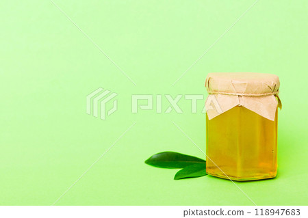 Honey in jar with leaves and honey dipper on colored background top view with copy text Honey in jar with leaves and honey dipper on colored background top view with copy text 118947683