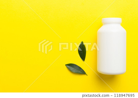 supplement pills with medicine bottle health care and medical top view. Vitamin tablets. Top view mockup bottle for pills and vitamins with green leaves, natural organic bio supplement, copy space 118947695