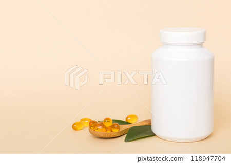 Omega-3 capsules lie in white bottle on a table with green leaves background. Fish oil tablets. Biologically active additives. omega 6, omega 9, vitamin A, E, D, vitamin D3 top view with copy space 118947704