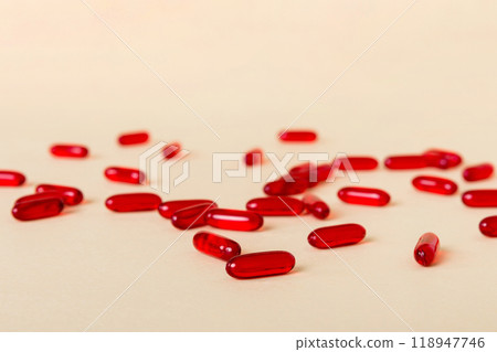 Heap of red pills on colored background. Tablets scattered on a table. Pile of red soft gelatin capsule. Vitamins and dietary supplements concept Heap of red pills on colored background. Tablets scattered on a table. Pile of red soft gelatin capsule. Vitamins and dietary supplements concept 118947746