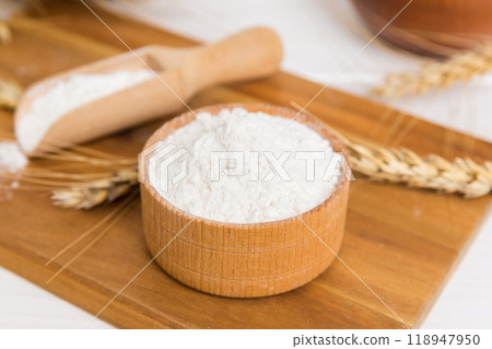 Flat lay of Wheat flour in wooden bowl with wheat spikelets on colored background. world wheat crisis Flat lay of Wheat flour in wooden bowl with wheat spikelets on colored background. world wheat crisis 118947950