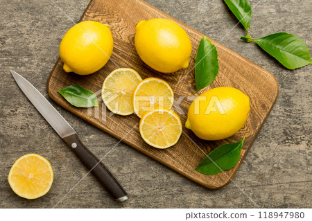 Top view with copy space for fresh and ripe lemons on cutting board. Healthy food background. Elegant background of lemon and lemon slices with squeezer and knife colored background 118947980