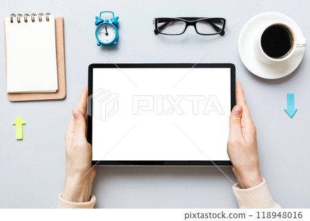 Close up image woman hands holding digital tablet with blank copy space screen for your text message or promotional content om table with cup of coffee. hands of a woman holding blank tablet device Close up image woman hands holding digital tablet with blank copy space screen for your text message or promotional content om table with cup of coffee. hands of a woman holding blank tablet device 118948016