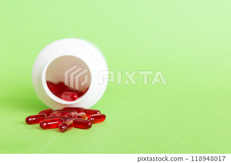 Red pills spilled around a pill bottle. Medicines and prescription pills flat lay background. Red medical capsules Red pills spilled around a pill bottle. Medicines and prescription pills flat lay background. Red medical capsules 118948017