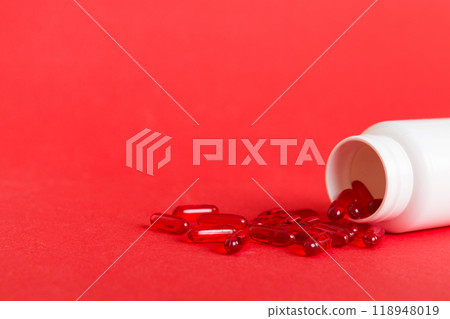 Red pills spilled around a pill bottle. Medicines and prescription pills flat lay background. Red medical capsules Red pills spilled around a pill bottle. Medicines and prescription pills flat lay background. Red medical capsules 118948019