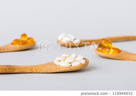Vitamin capsules in a spoon on a colored background. Pills served as a healthy meal. Red soft gel vitamin supplement capsules on spoon Vitamin capsules in a spoon on a colored background. Pills served as a healthy meal. Red soft gel vitamin supplement capsules on spoon 118948032
