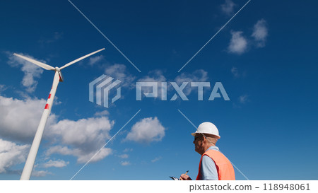 Engineer walks under wind turbines Engineer walks under wind turbines 118948061