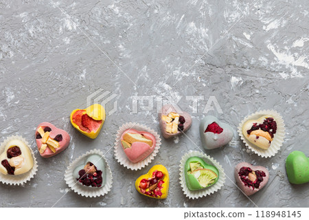 chocolate sweets in the form of a heart with fruits and nuts on a colored background. top view with space for text, holiday concept 118948145