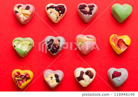 chocolate sweets in the form of a heart with fruits and nuts on a colored background. top view with space for text, holiday concept 118948146