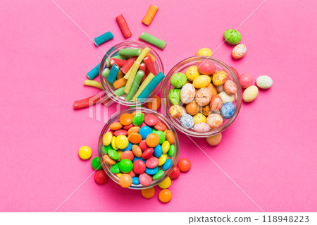 different colored round candy in bowl and jars. Top view of large variety sweets and candies with copy space different colored round candy in bowl and jars. Top view of large variety sweets and candies with copy space 118948223