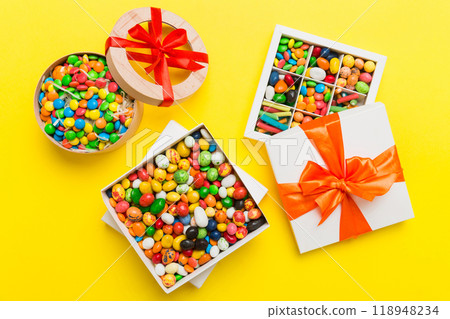 Set of different sweet candy in a paper box with a satin ribbon on a colored background. Holiday concept 118948234