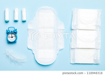 Ringing alarm clock with sanitary female tampons and menstrual sanitary pads. Medical concept of woman critical days and menstruation. Female daily hygiene. Copy space 118948318