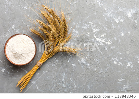 Flat lay of Wheat flour in wooden bowl with wheat spikelets on colored background. world wheat crisis 118948340