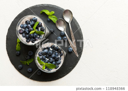 Healthy breakfast or morning with chia seeds vanilla pudding and blueberry berries on table background, vegetarian food, diet and health concept. Chia pudding with coconut milk and blueberry Healthy breakfast or morning with chia seeds vanilla pudding and blueberry berries on table background, vegetarian food, diet and health concept. Chia pudding with coconut milk and blueberry 118948366